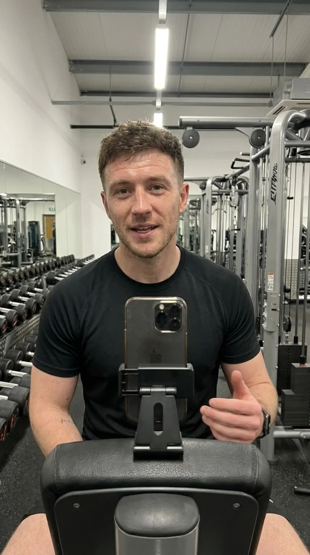 Personal trainer running a paid form check on his phone at the gym